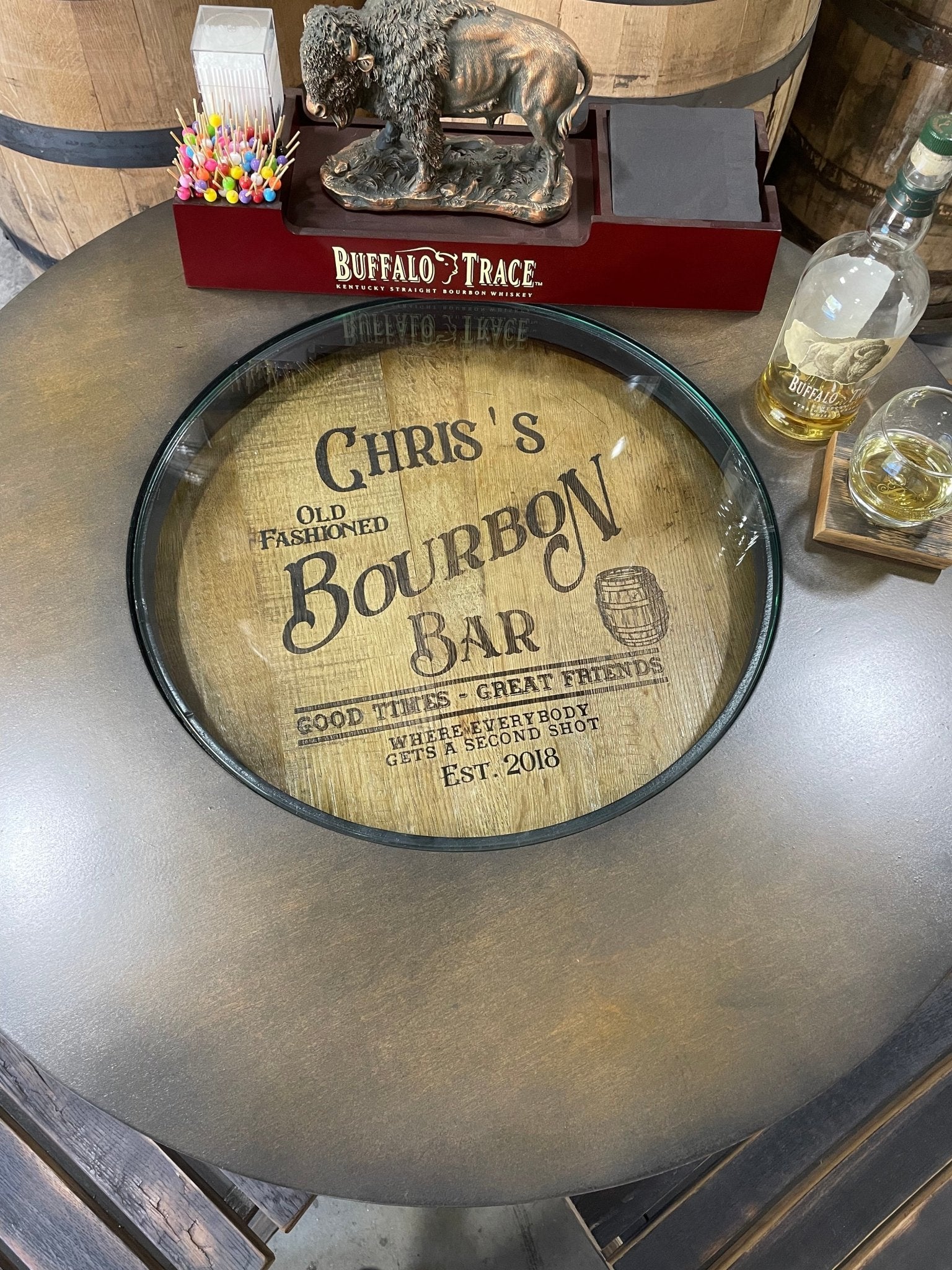 Bespoke bourbon barrel bistro table with personalized glass top viewing portals for curated private estate spirit displays.