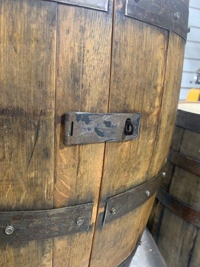 Architectural bourbon barrel cabinet outfitted with heavy-duty metal locking hasp hardware and magnetic door closure systems.