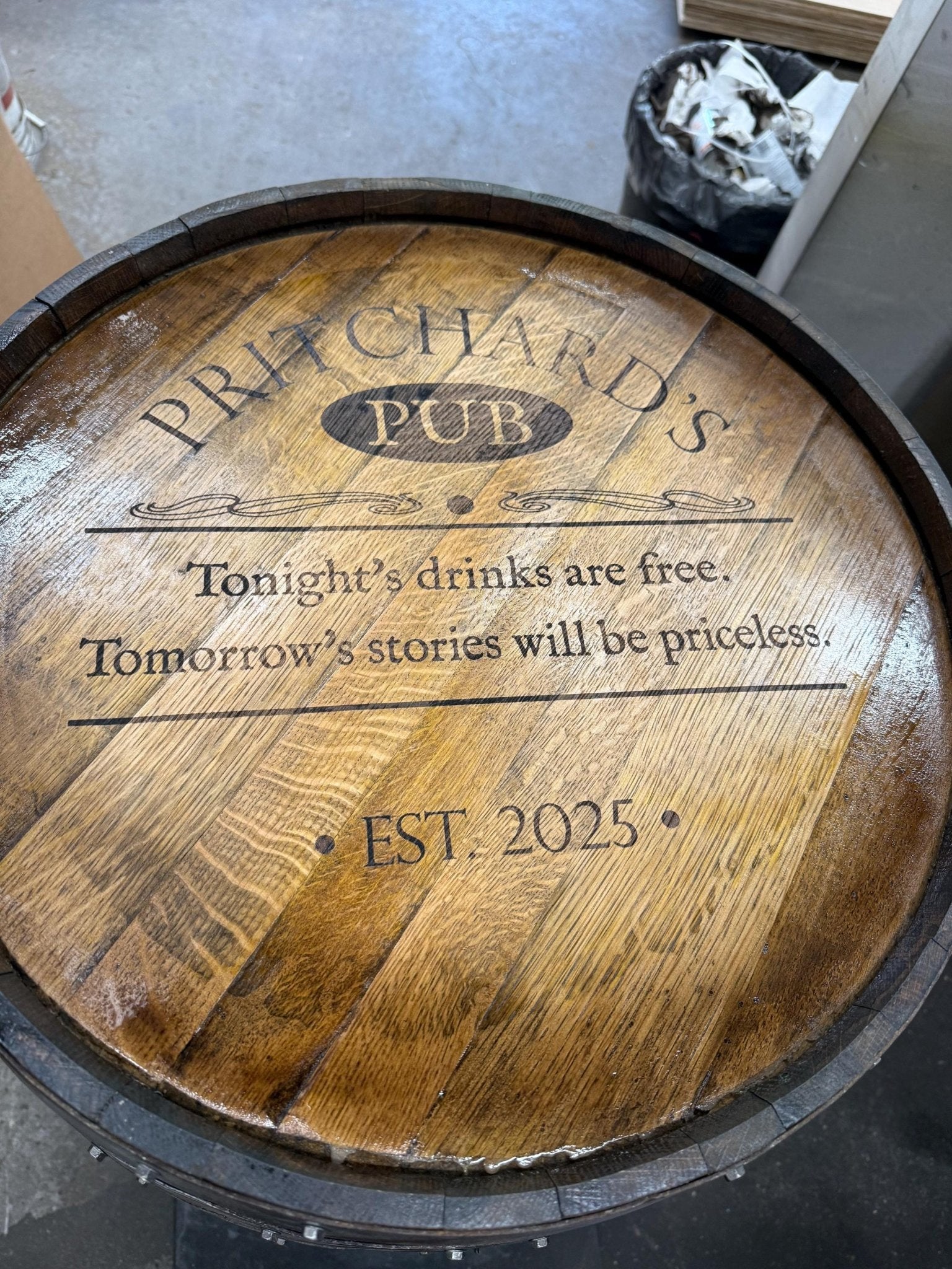 Custom barrel table showcasing laser-etched private club seal engraving on clear-coated reclaimed oak barrel wood