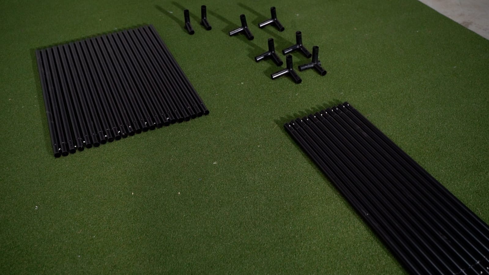 SimBox golf simulator enclosure frame components laid out – complete assembly kit on green mat