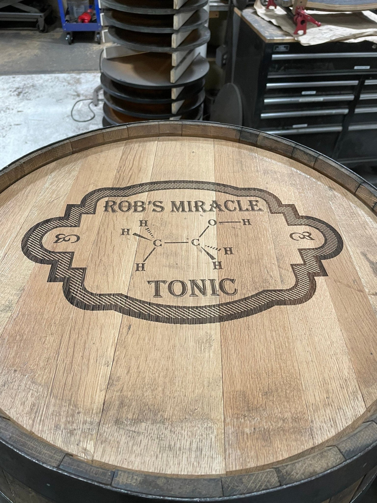 Bespoke whiskey billiards cue cabinet customized with vintage apothecary typography etched directly onto oak barrel heads.