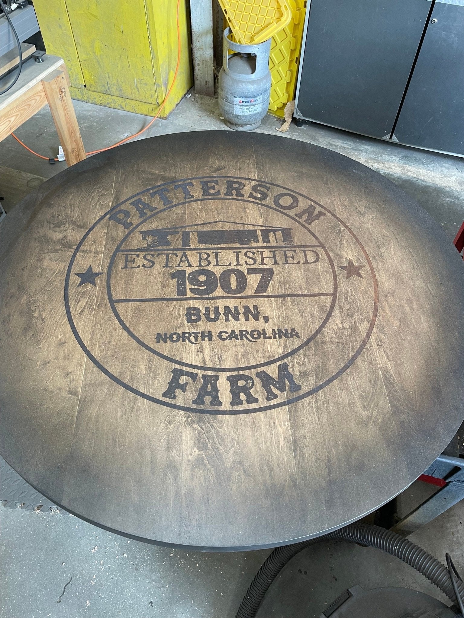 Architectural bourbon barrel table customized with precision laser-engraved family crests and protective topcoat finishes.