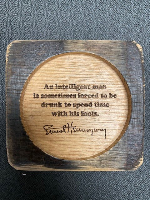 Custom whiskey quote coasters featuring laser-engraved Hemingway reflections inside protective clear-coated circular wells.