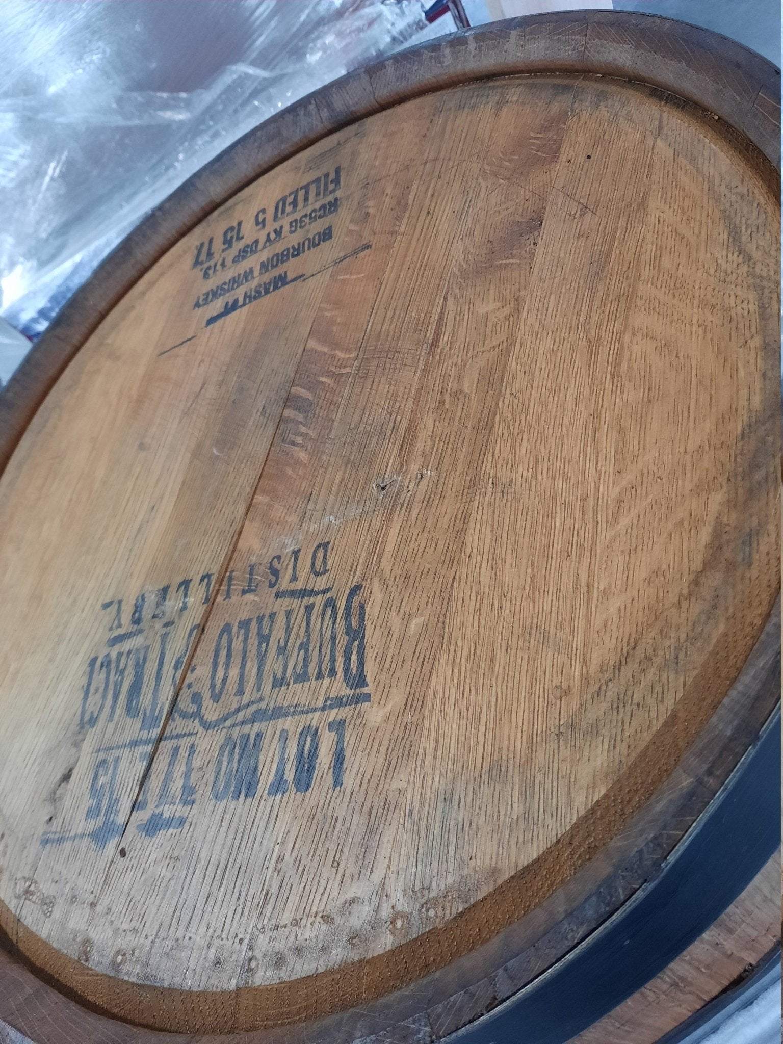 Heritage bourbon barrel cabinet preserving authentic distillery head stamps beneath protective clear-lacquered topcoats.