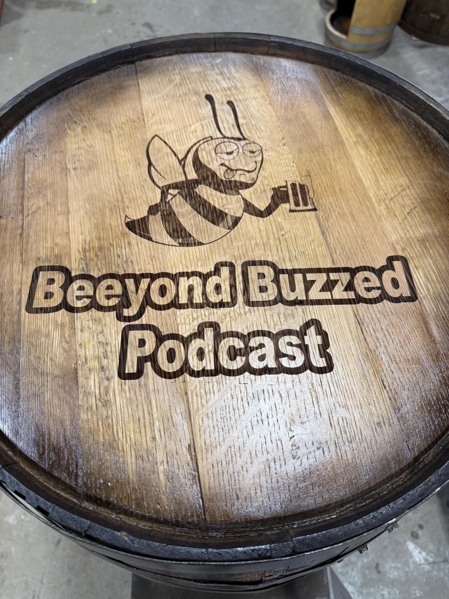 Handcrafted bourbon barrel table featuring custom podcast logo laser etching on sealed hand sanded solid oak wood barrel top