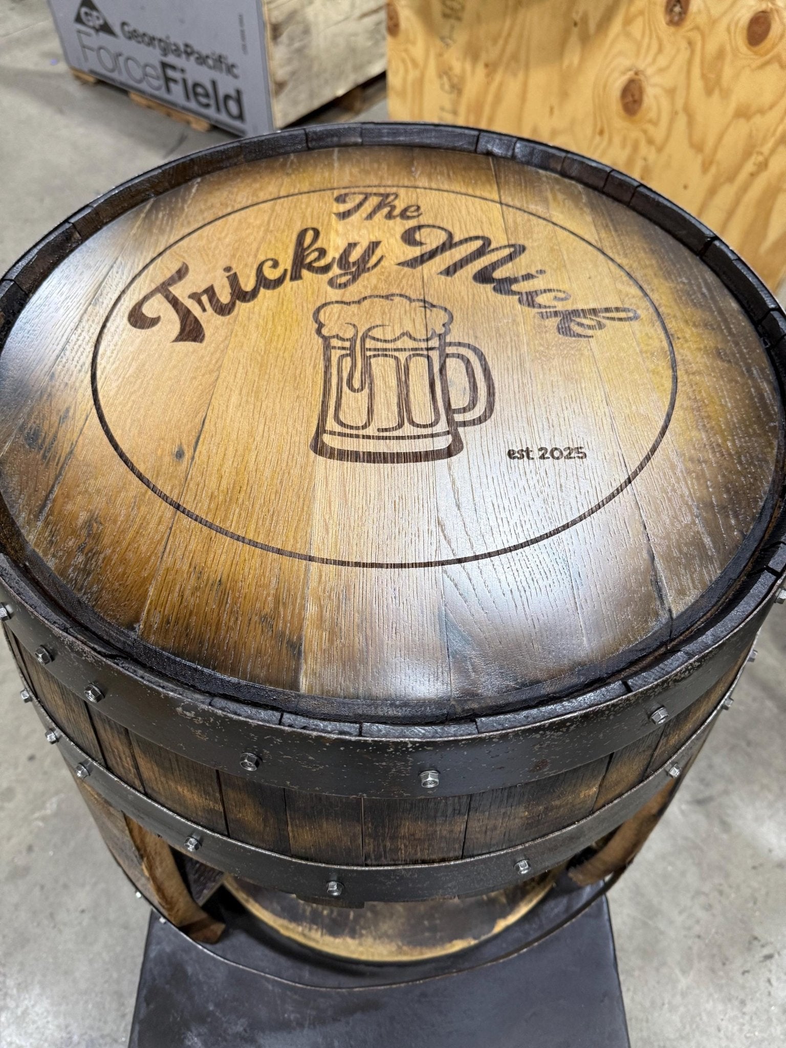 Handcrafted bourbon barrel table showcasing custom laser burned pub logo art on genuine spirit stained oak barrel top head