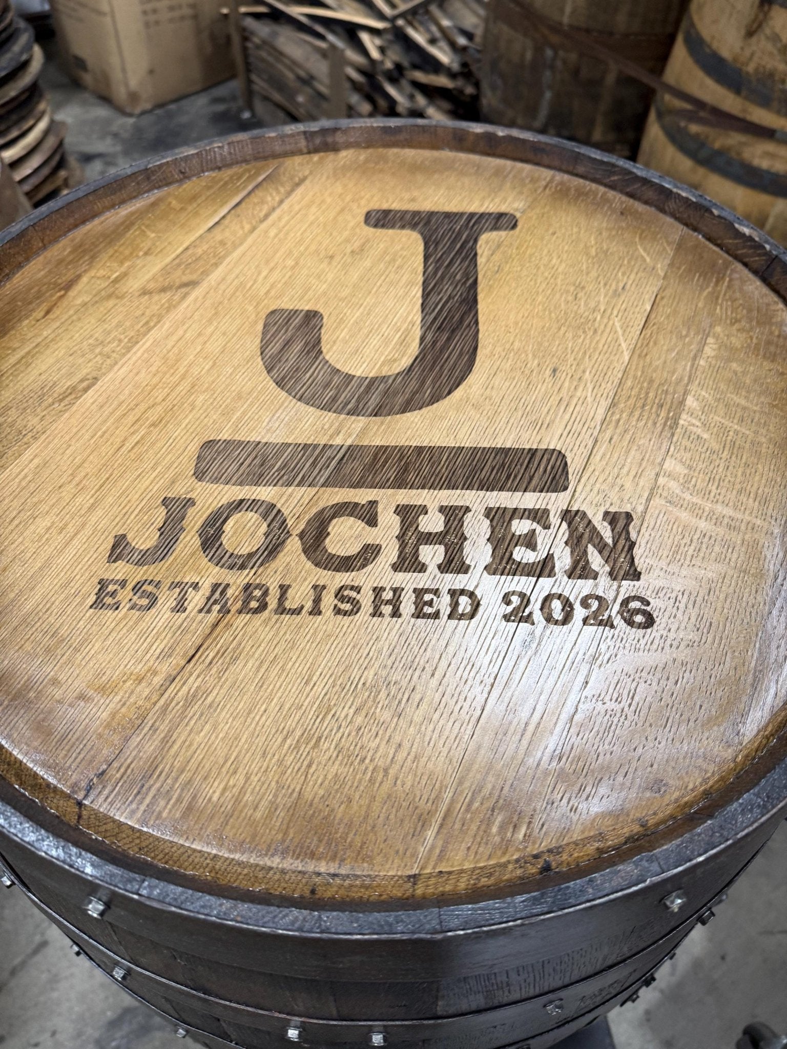 Bespoke bourbon barrel table engineered with custom initial monogram laser etching on authentic solid oak whiskey barrel head