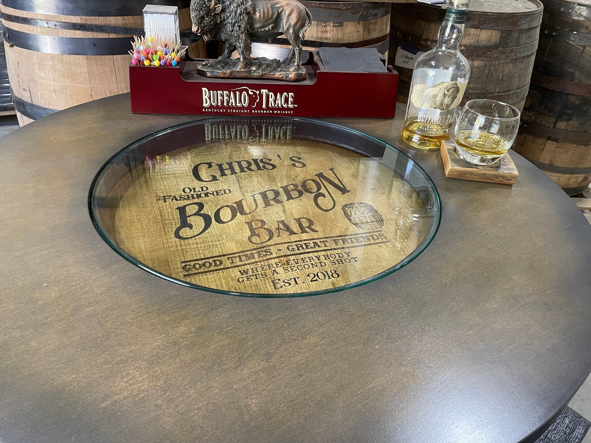 Artisan bourbon barrel table featuring central glass top cutout displaying custom laser engraved whiskey barrel head graphics