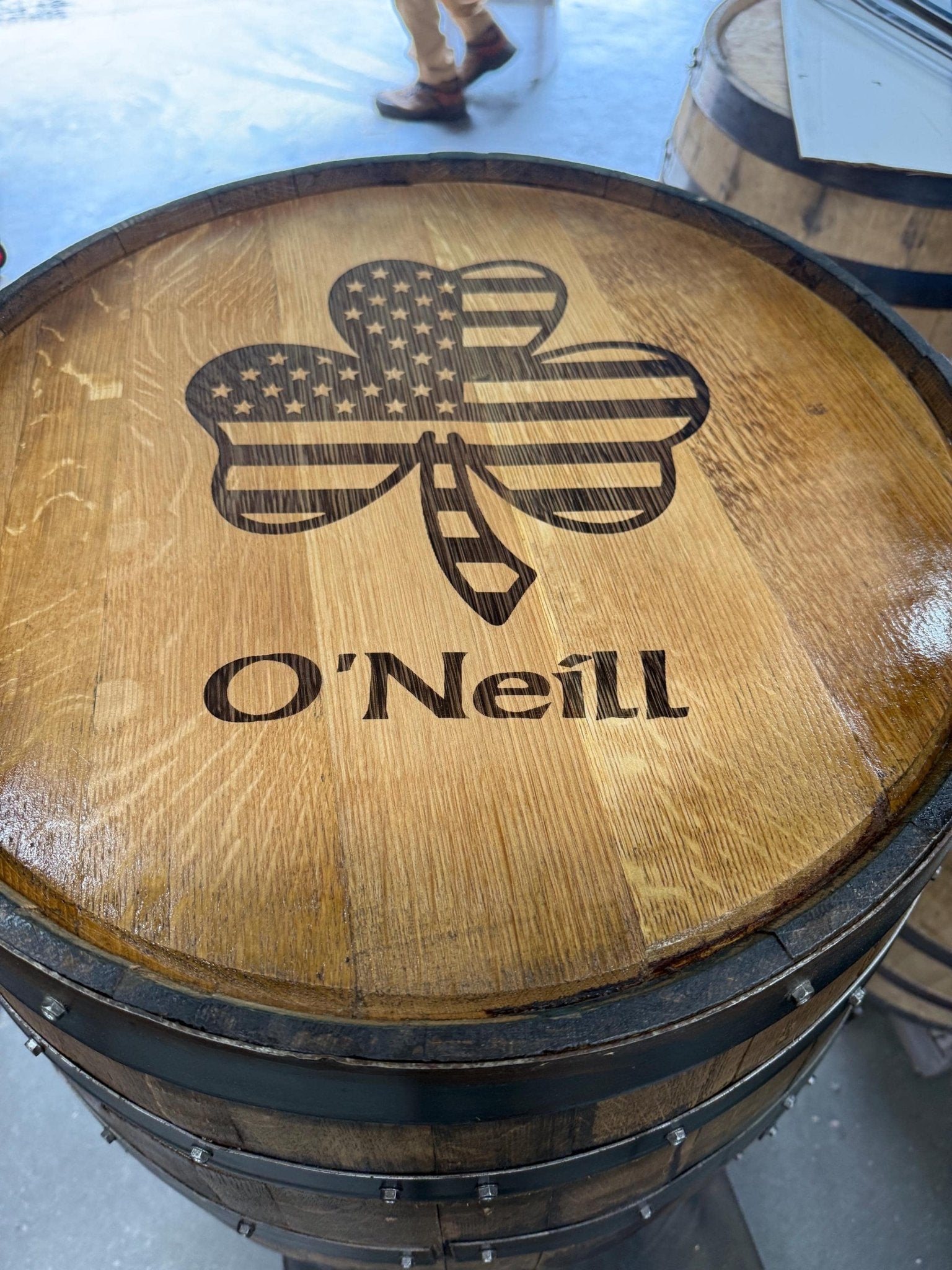 Handcrafted bourbon barrel table displaying custom shamrock family crest laser engraving on authentic solid oak barrel head