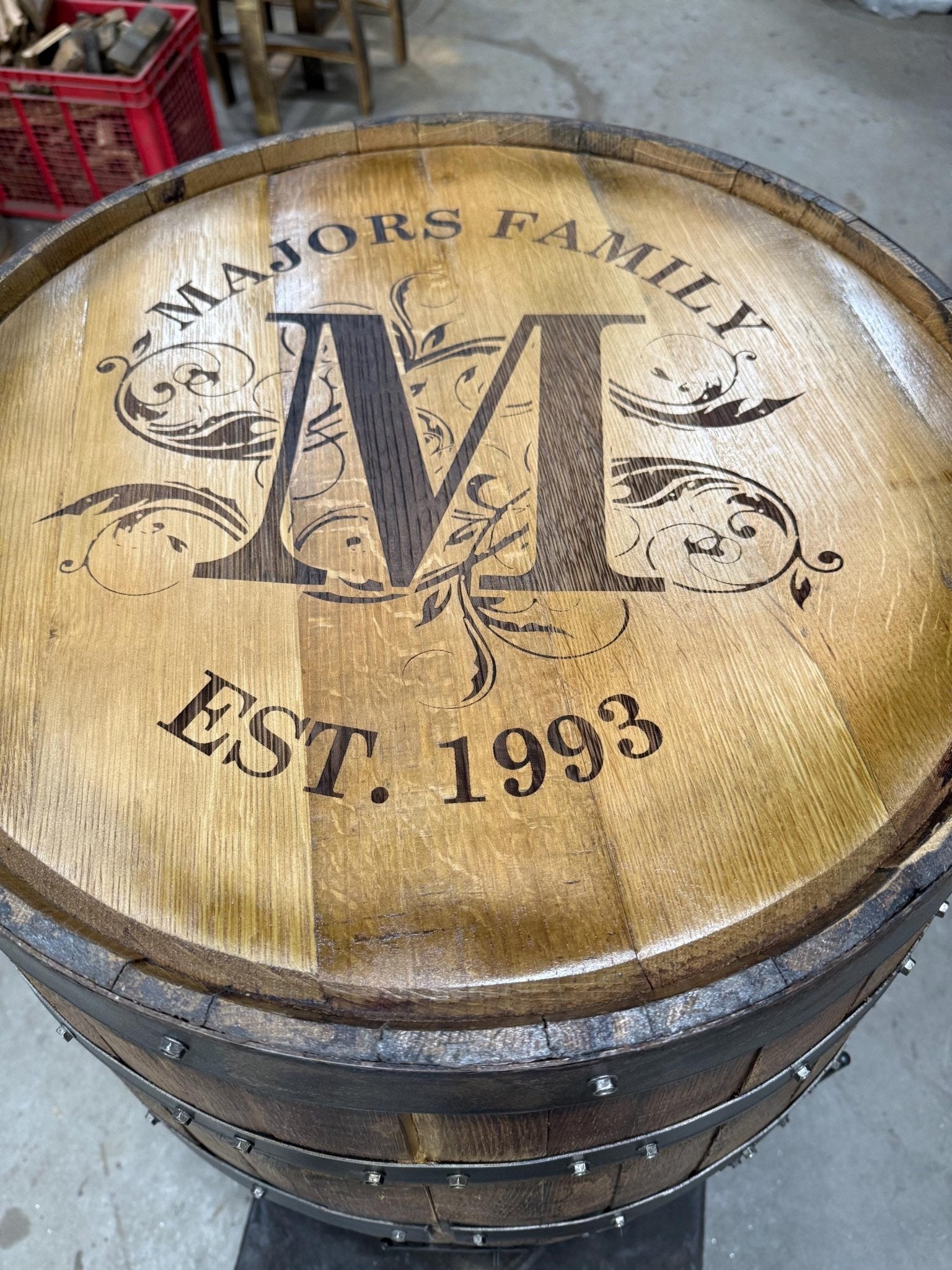 Custom bourbon barrel table built with personalized family crest monogram laser engraving on authentic whiskey barrel head