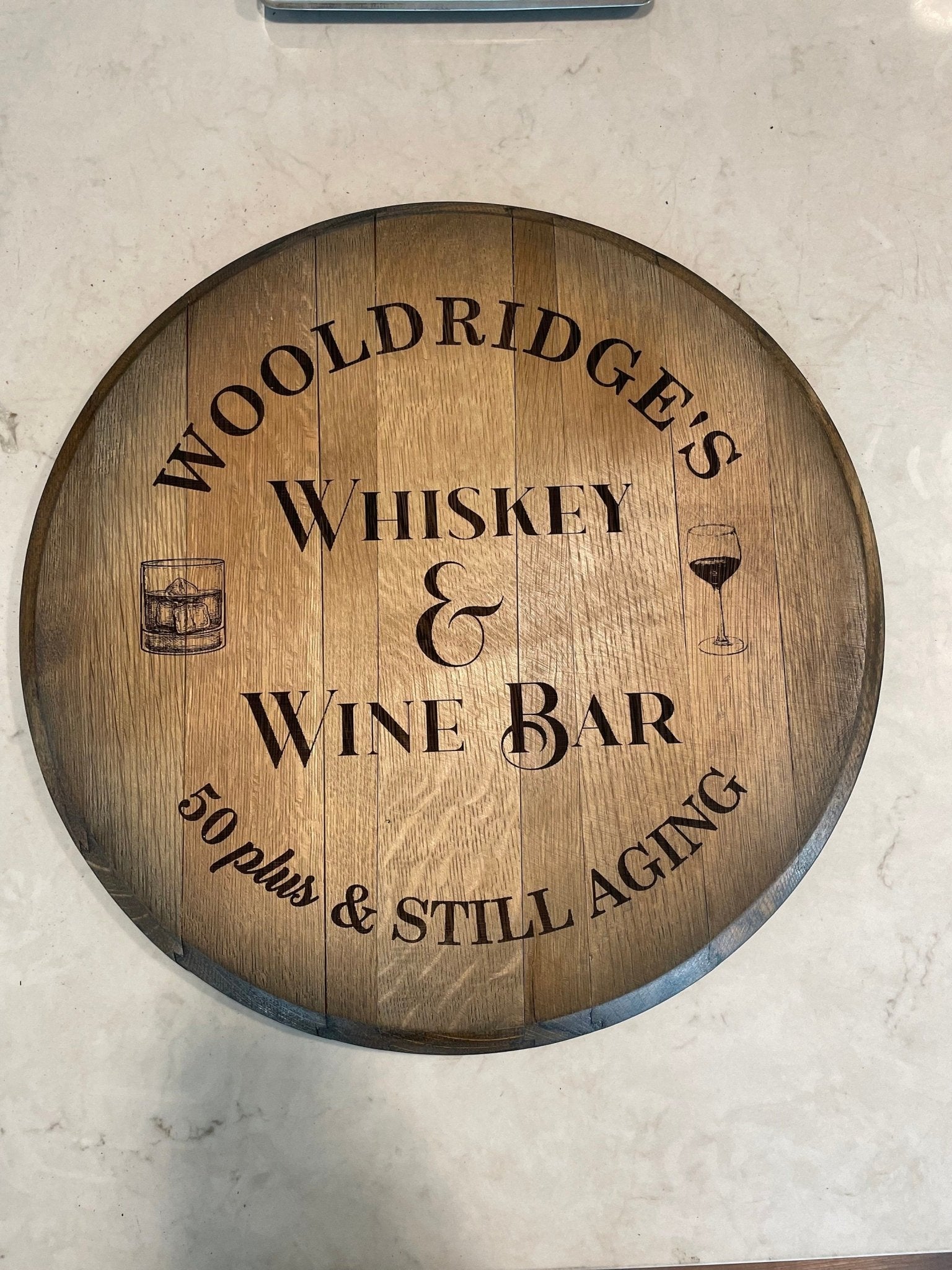 Custom barrel table featuring precision laser-carved custom branding on authentic aged clear-coated whiskey barrel head
