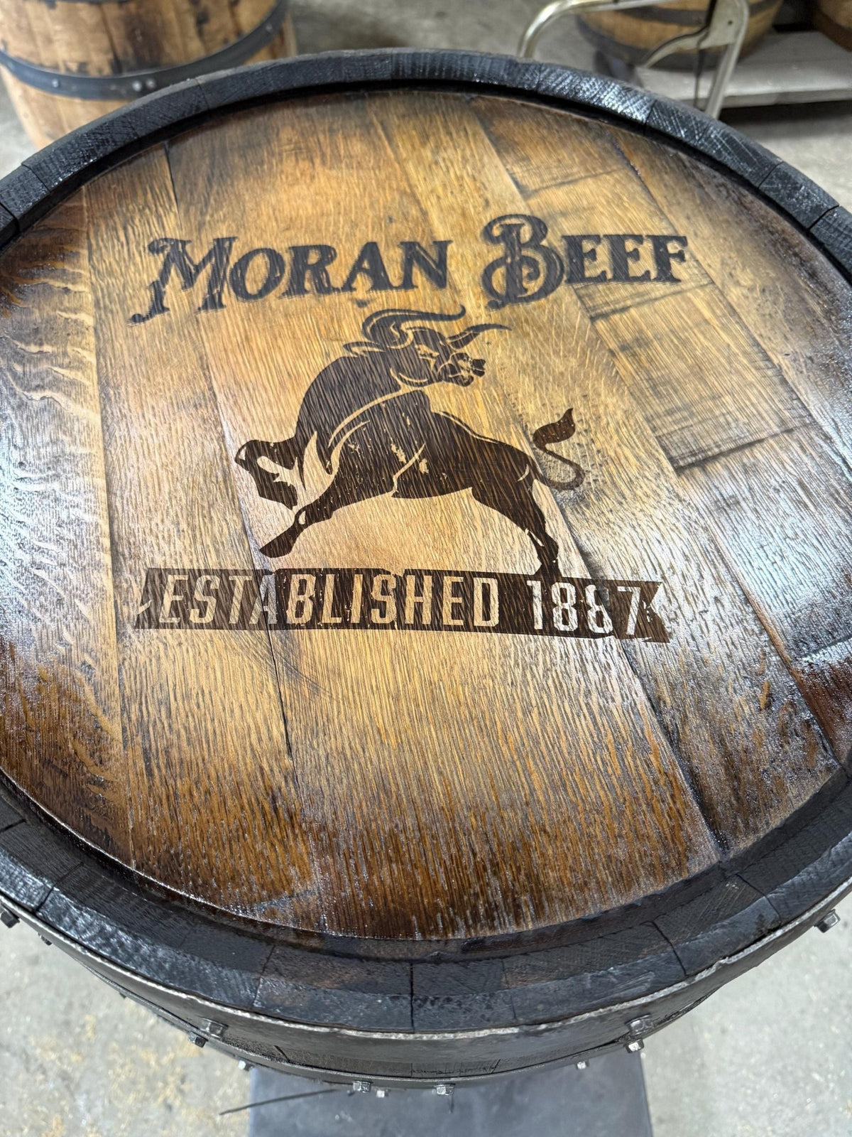 Artisan whiskey billiards cue cabinet customized with detailed ranch insignia laser-etched into solid white oak barrel heads.