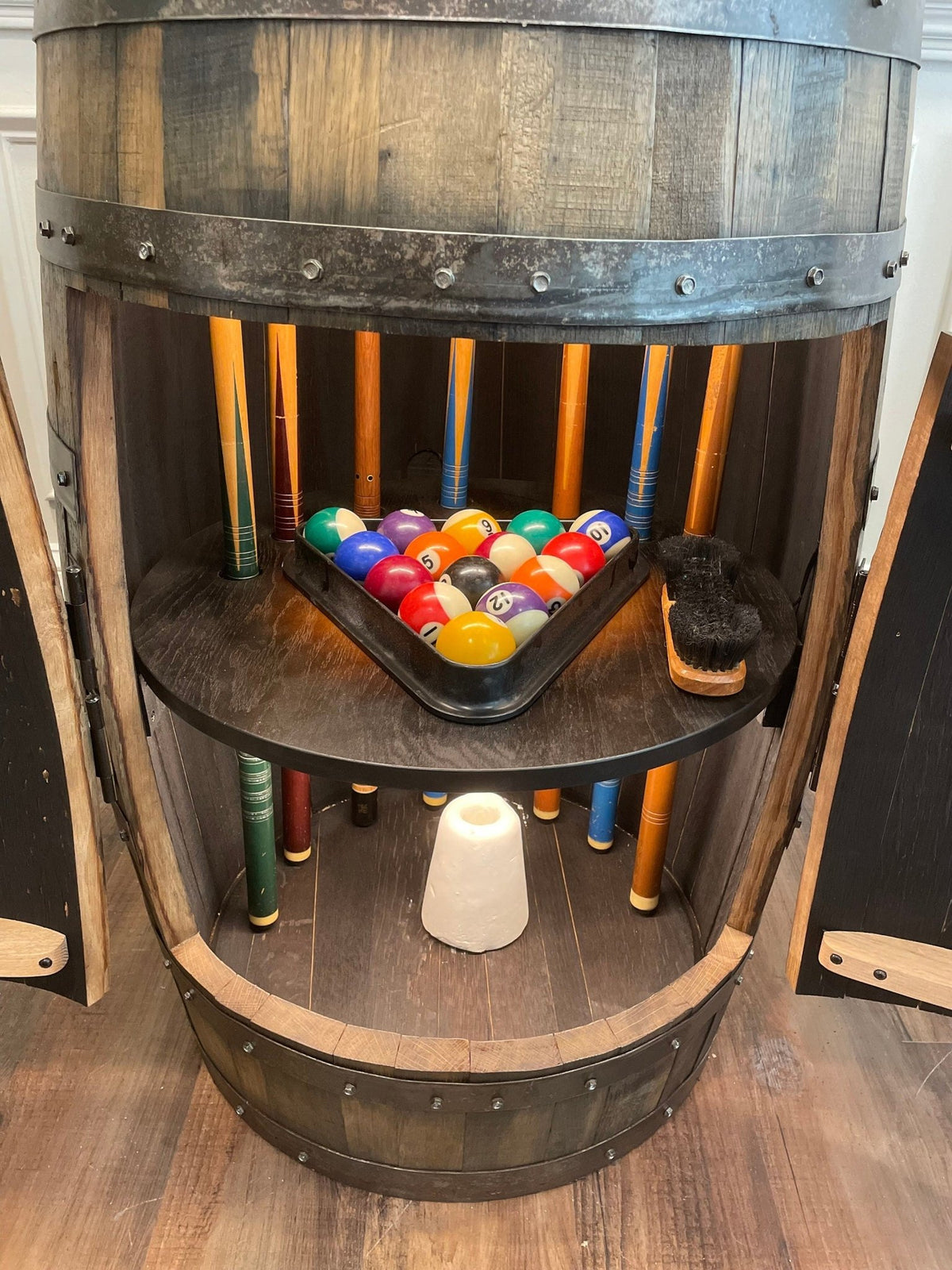 Artisan whiskey billiards cue cabinet displaying handcrafted starburst oak shelf details beneath automated LED fixtures.